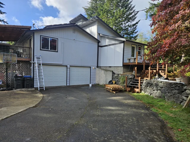 The same Port Orchard home's front exterior later in the project, with light paint and dark trim; ladders and materials remain on site.